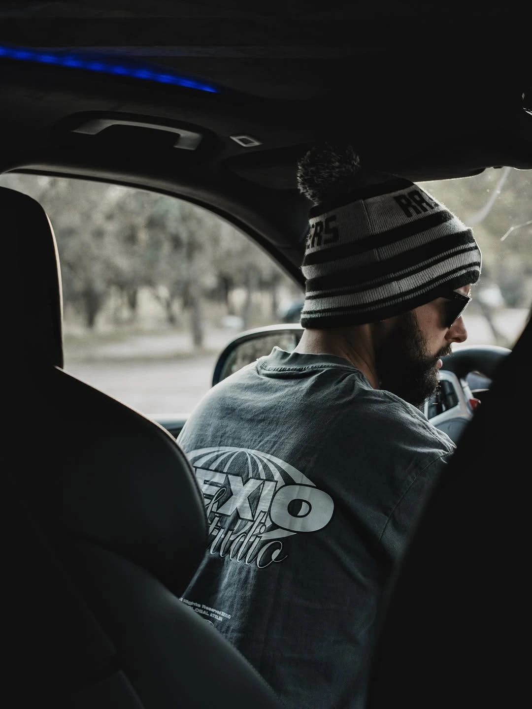 Persona con una camiseta de Zexio Brand en un coche de alta gama