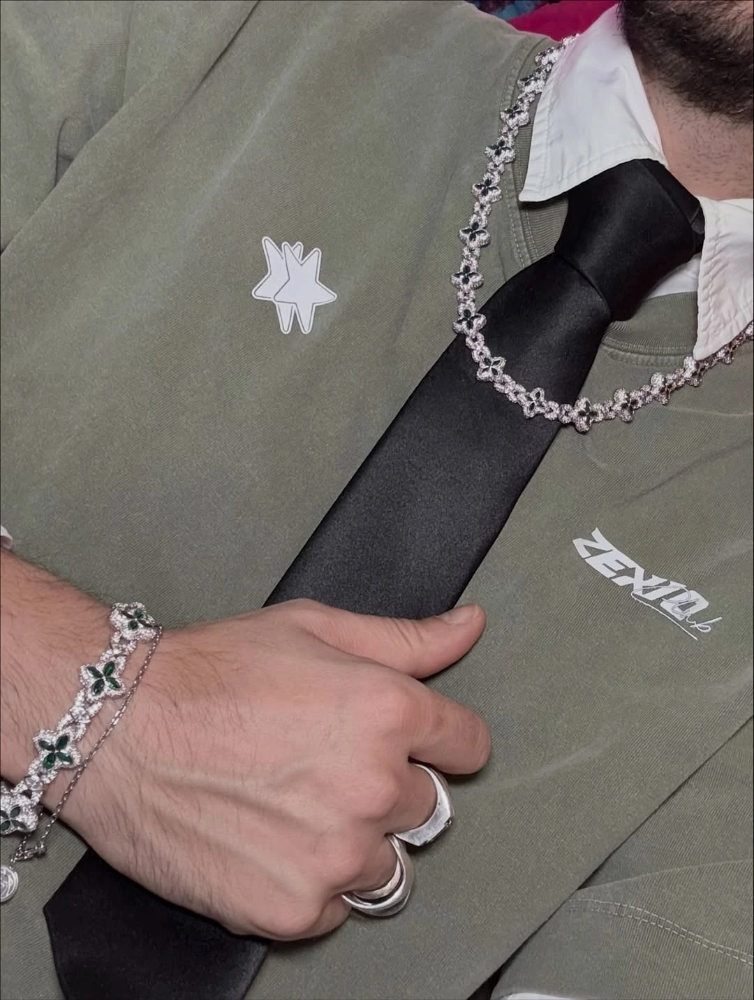 Hombre con colgantes de lujo llevando una camiseta verde de la marca de ropa Zexio
